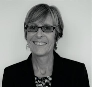 Lynne Drummond, wearing glasses and a dark jacket, looking to camera