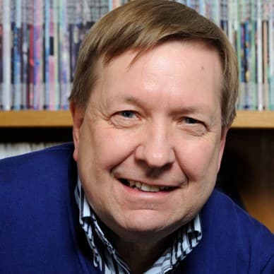 Trevor Robbins, smiling to camera in front of a bookshelf